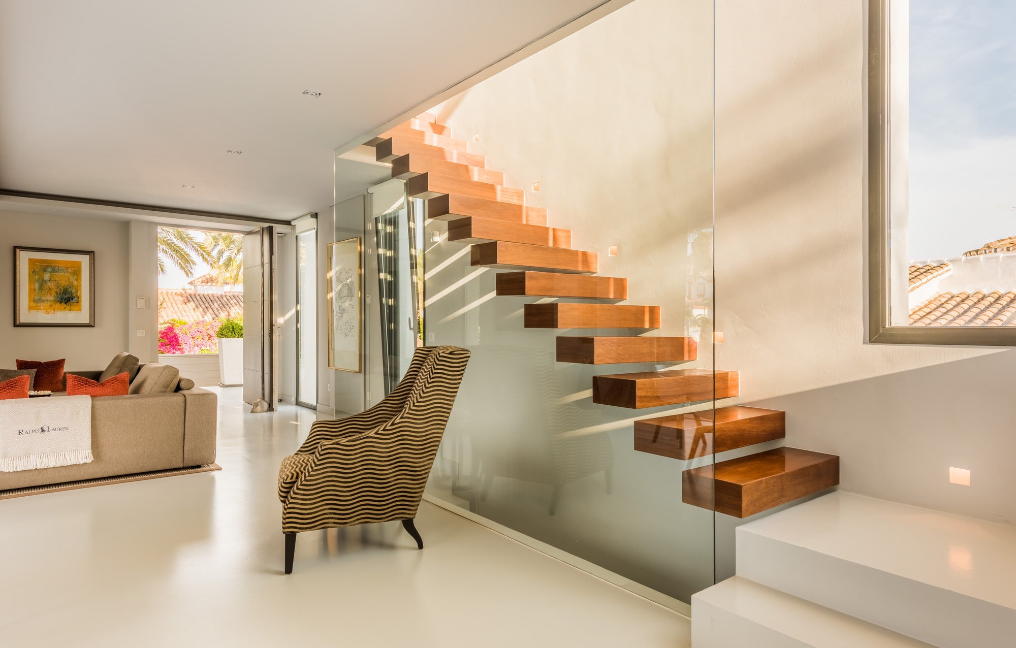 Interior living space at Villa Australia with floating staircase, warm lighting and contemporary Mediterranean softness