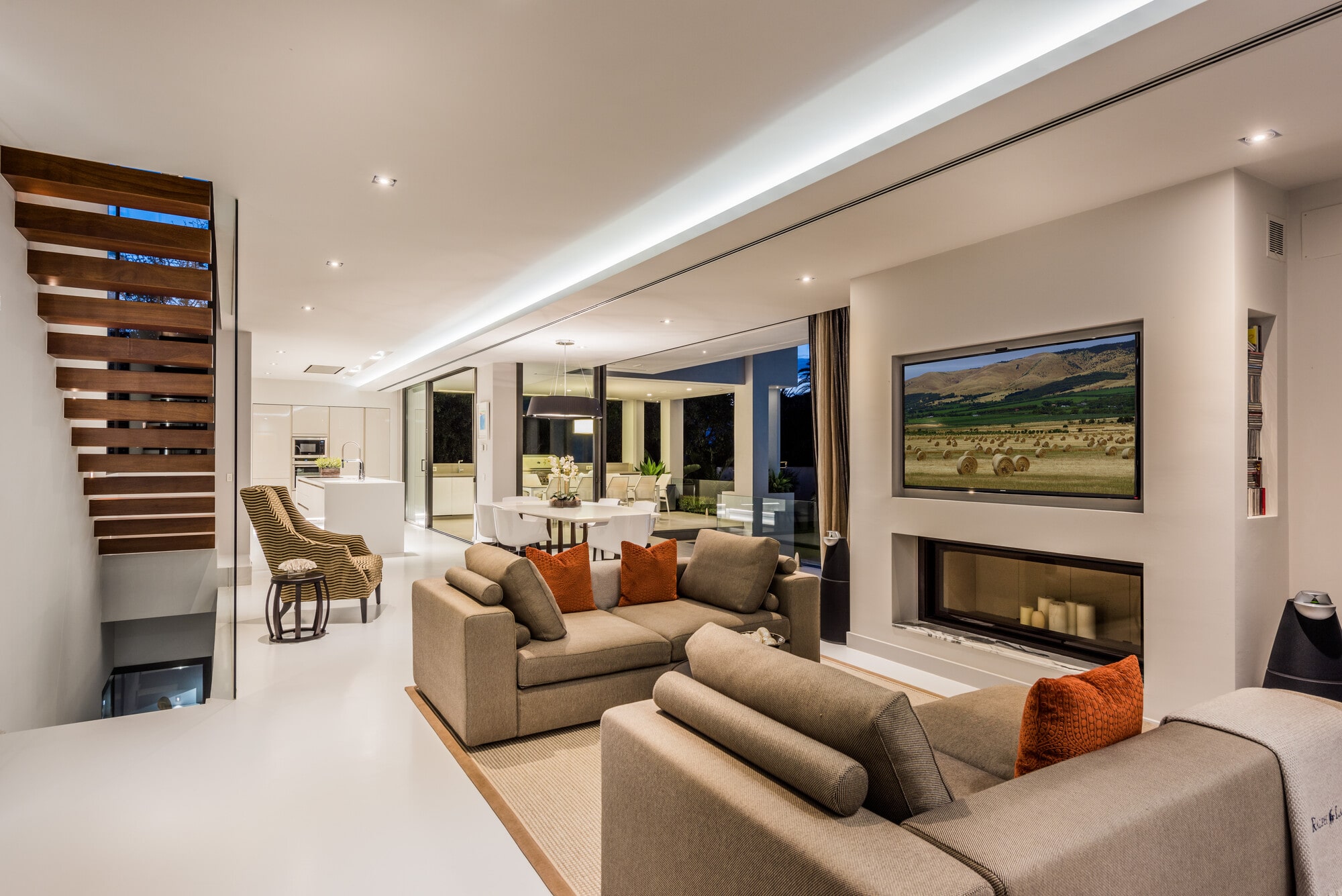 Main lounge at Villa Australia with fireplace wall, recessed lighting and long interior perspective