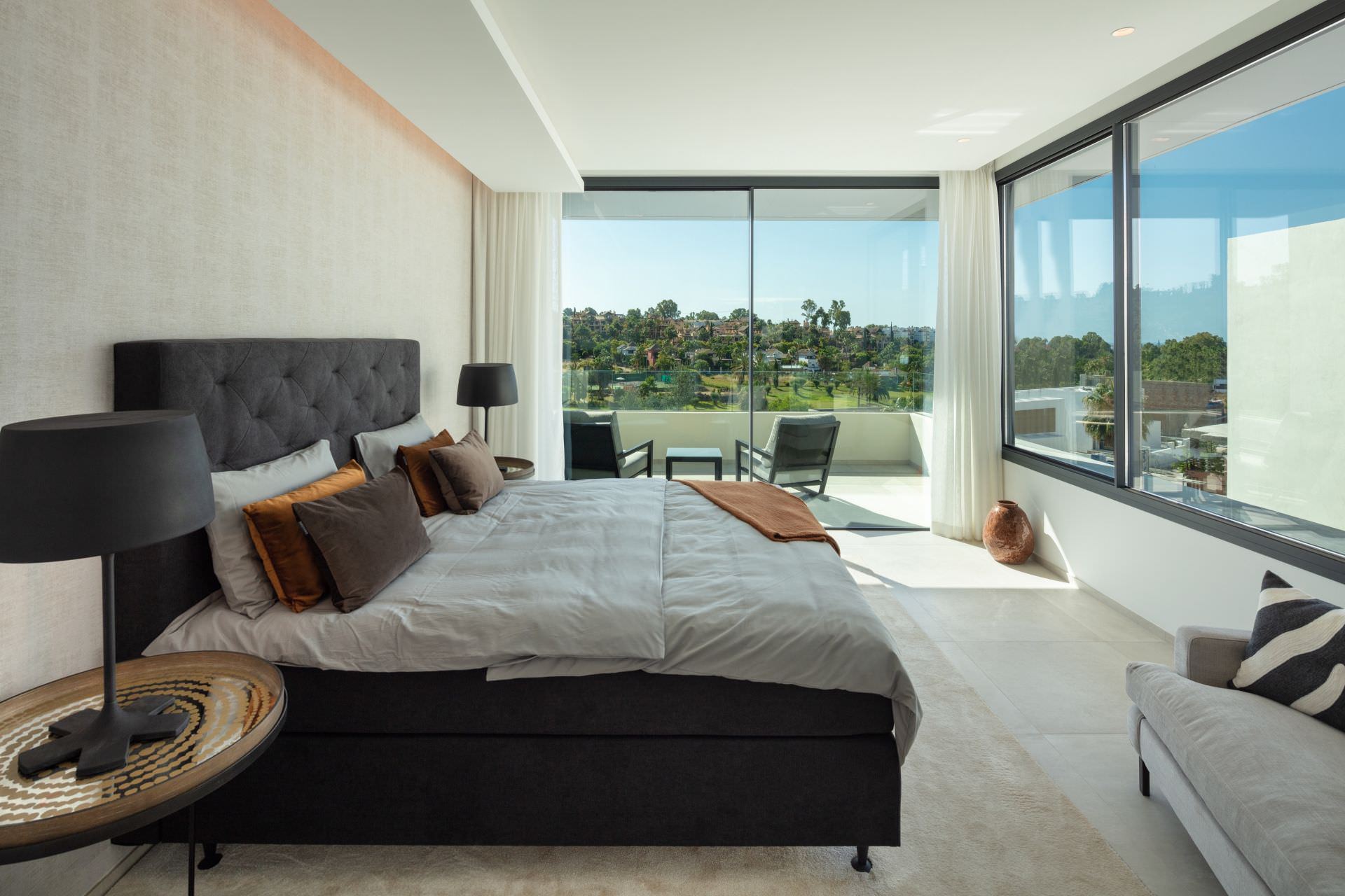 Bedroom suite at BELFRY with panoramic glazing and serene, softly lit interior palette