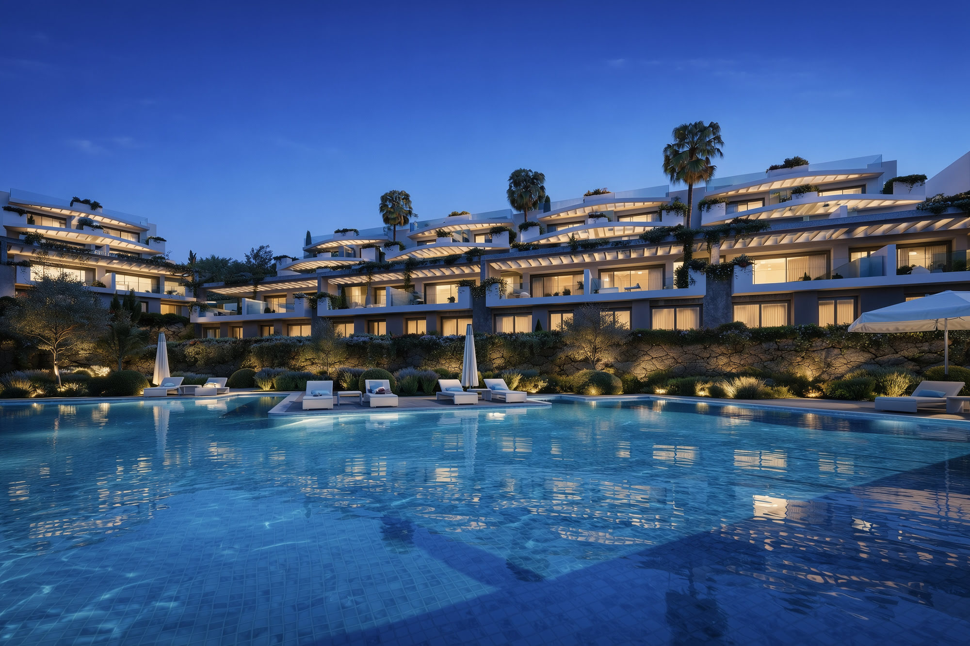 Night pool scene at CALASOL with warm façade lighting and blue water reflections in La Cala de Mijas