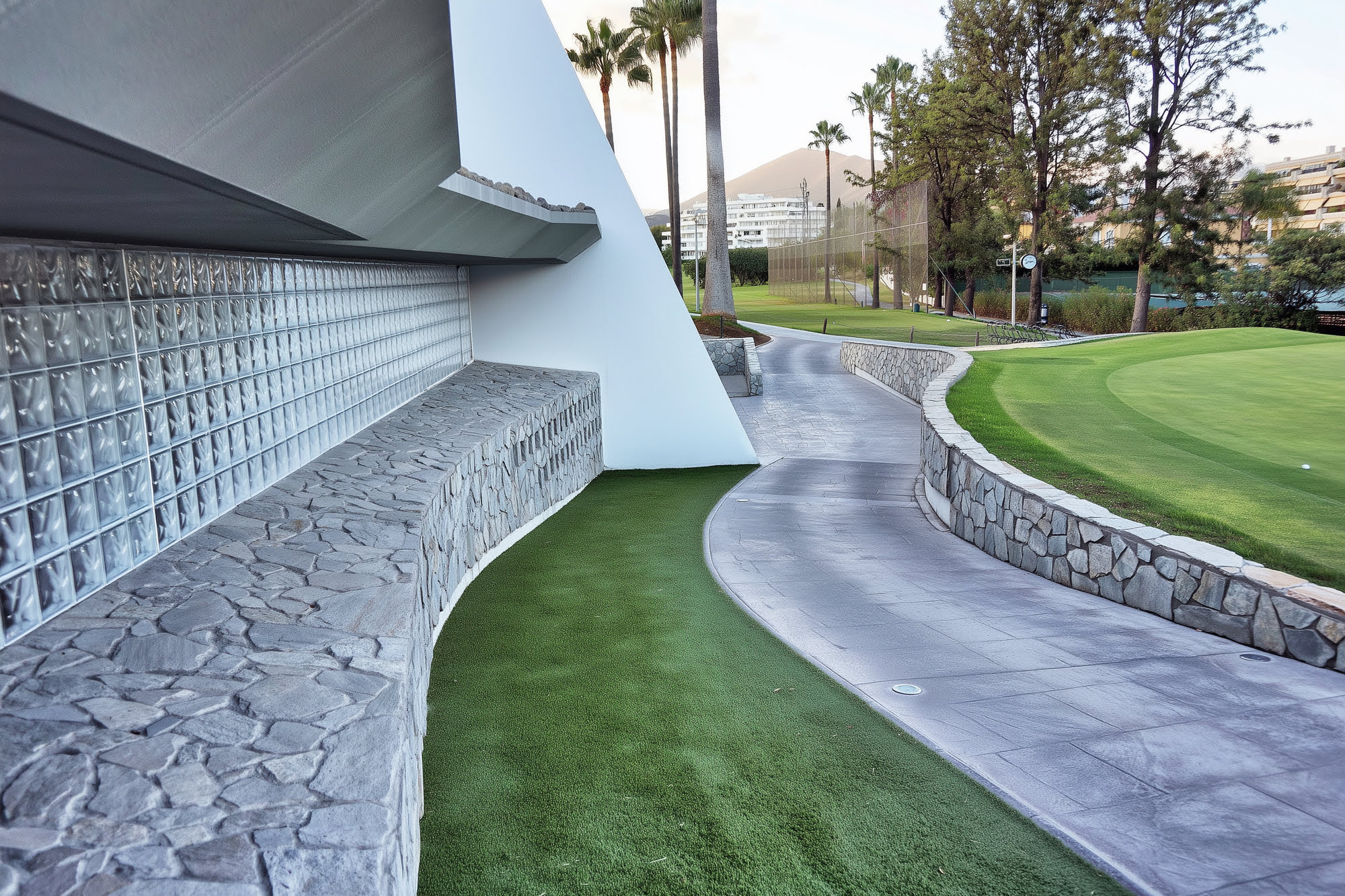 Stone base, glazed brick wall and curved path integrated into the clubhouse perimeter landscape