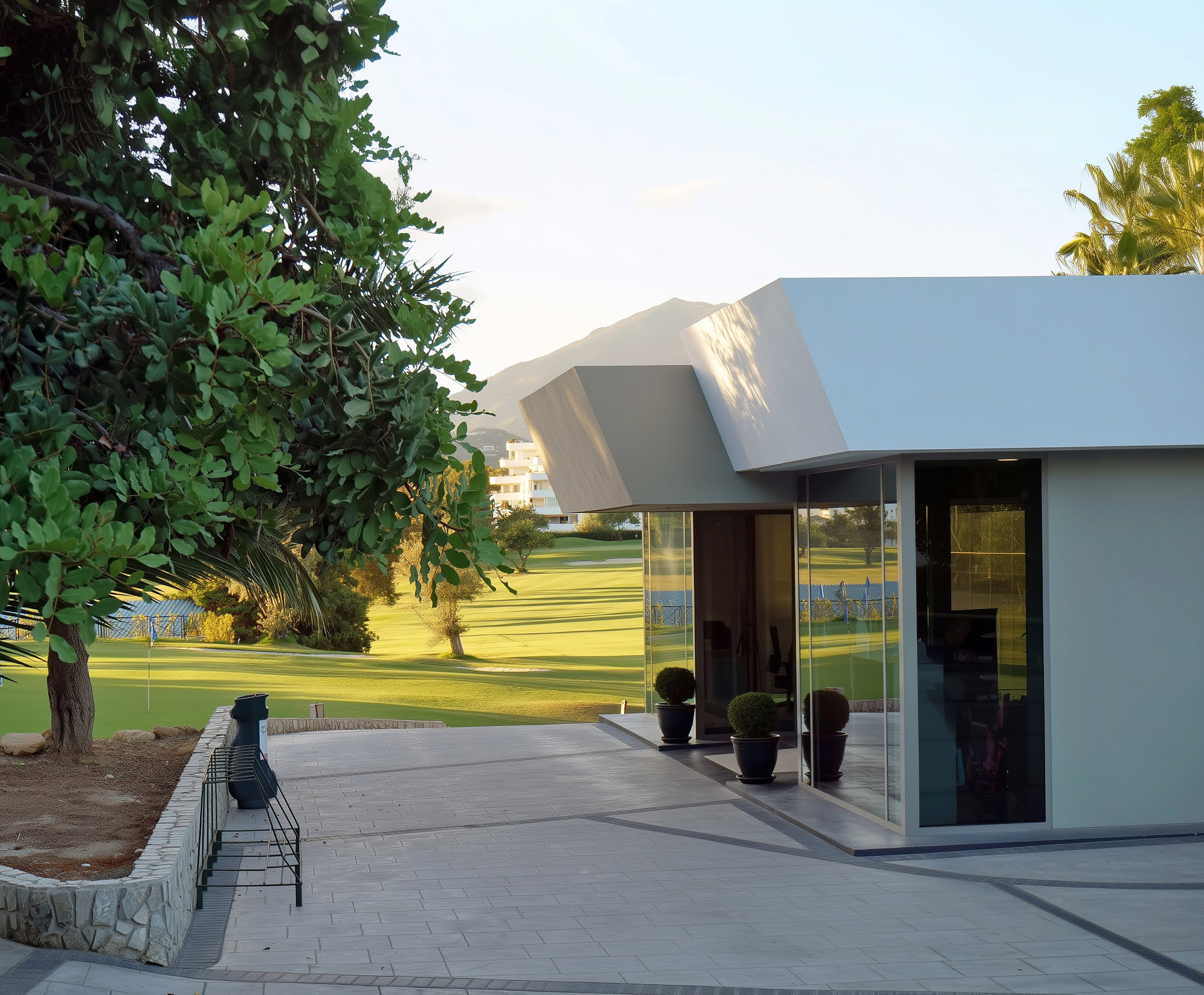 Entrance façade of the Guadalmina clubhouse framed by mature trees and paved arrival court
