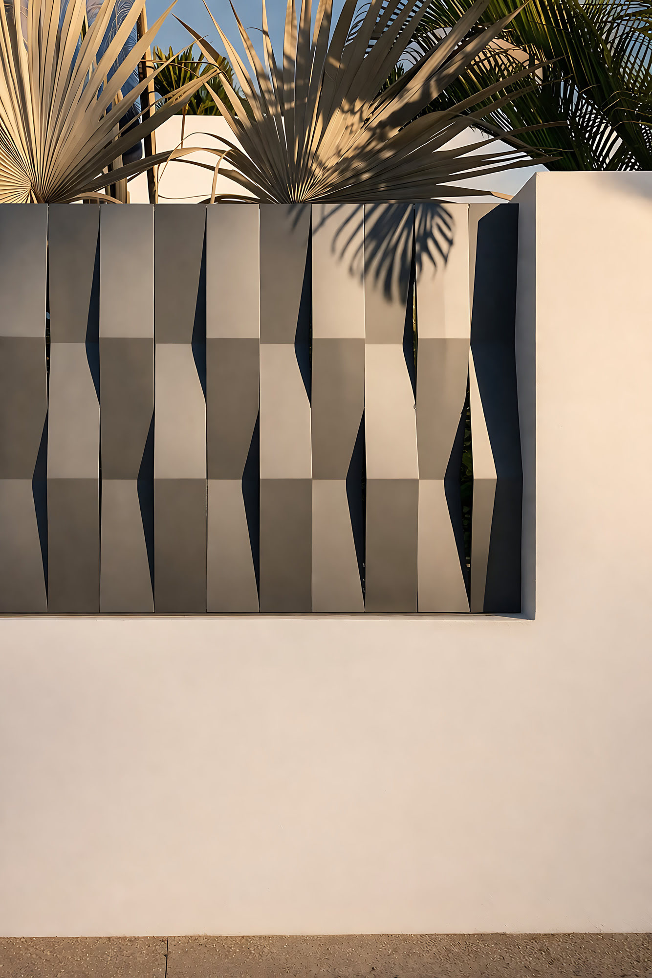 Architectural wall detail and sculptural exterior screening at DALÍ Villa with tropical planting and shadow play