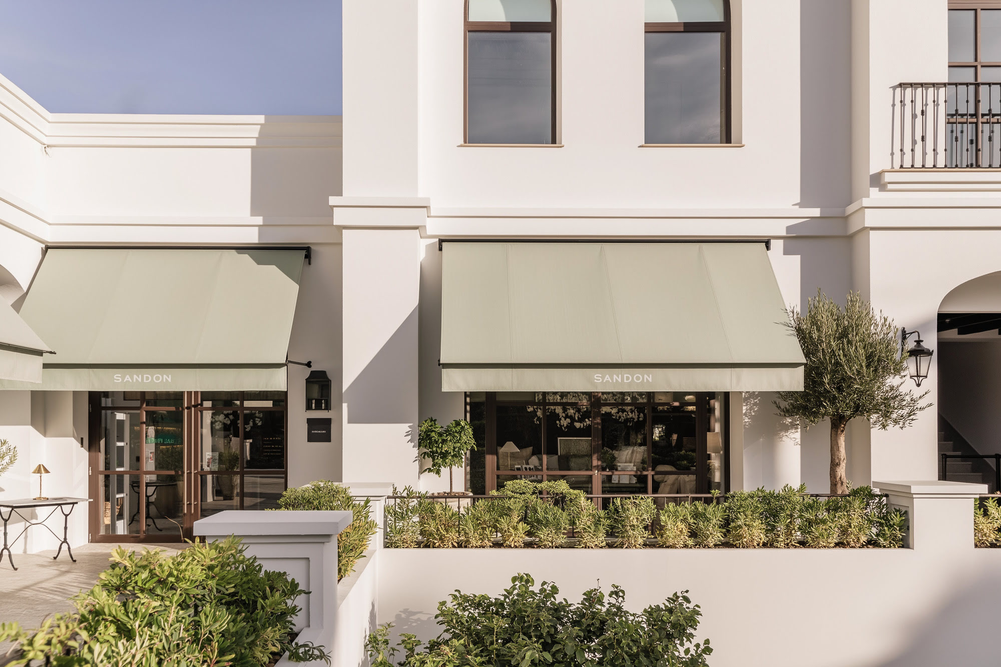 Street-facing architectural detail at FORUM with elegant shopfront rhythm, soft-toned façades and tailored awnings
