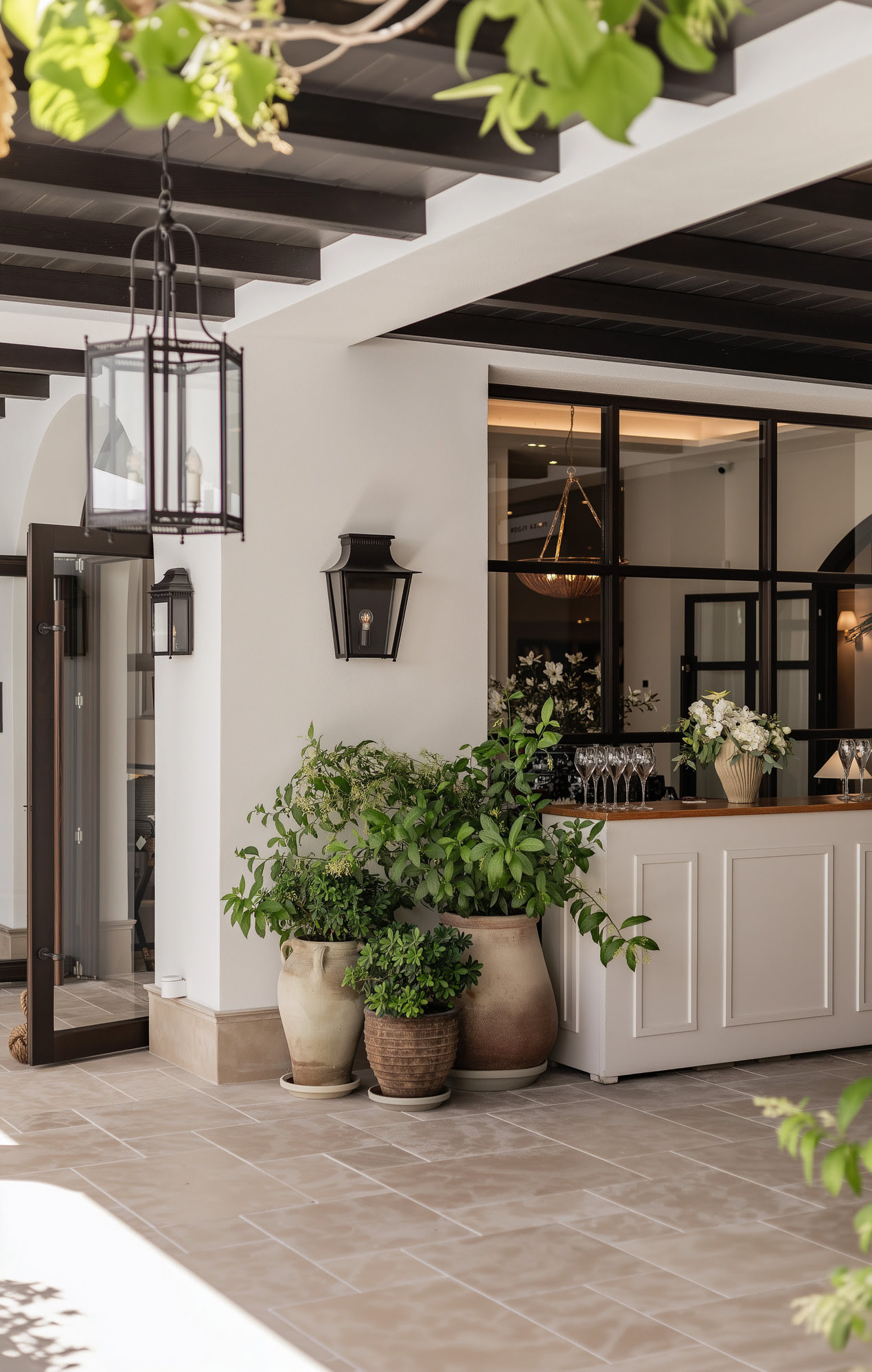Semi-covered hospitality threshold at FORUM with pergola beams, planted corners and intimate transition between exterior walkway and interior venue