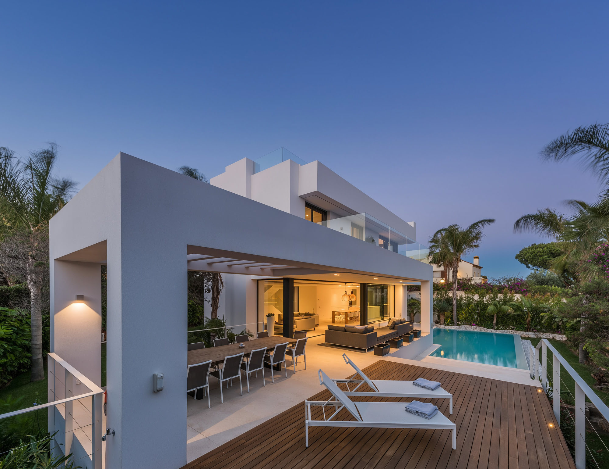 Blue hour outdoor lounge and pool terrace at M152 with warm lighting and garden setting