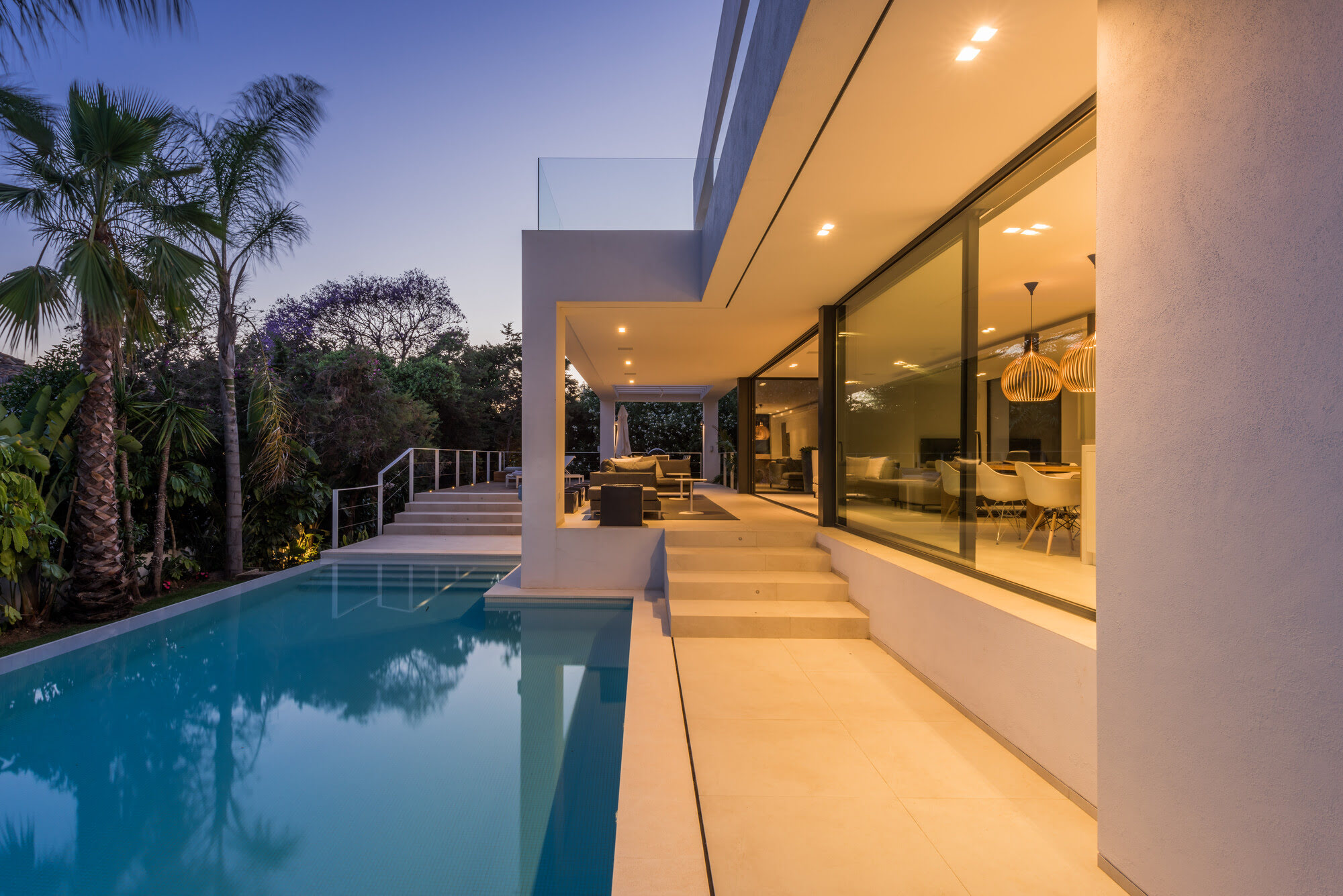 Evening view along the pool and glazed façade of M152 with warm interior lighting