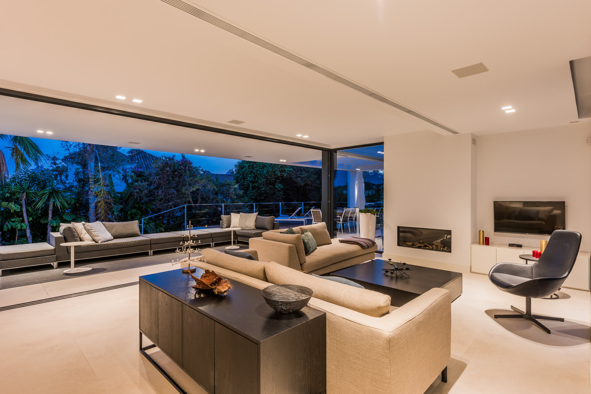 Evening interior of M152 with open sliding doors and seamless connection to the terrace and pool
