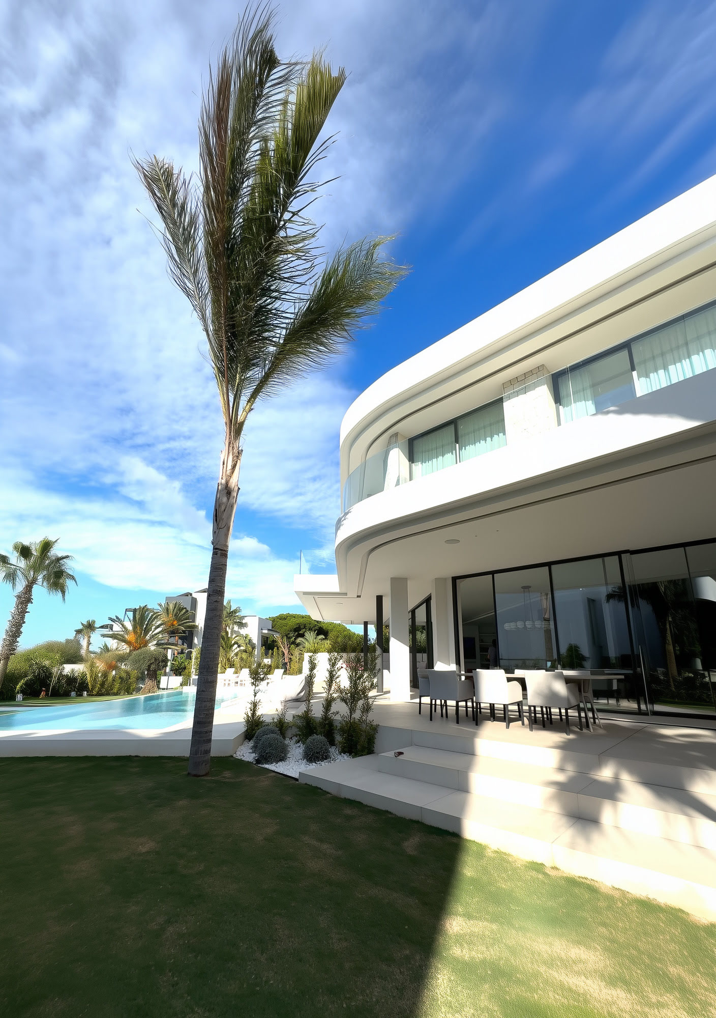 Side garden view of an M94 villa with lawn, palm tree and shaded outdoor living edge