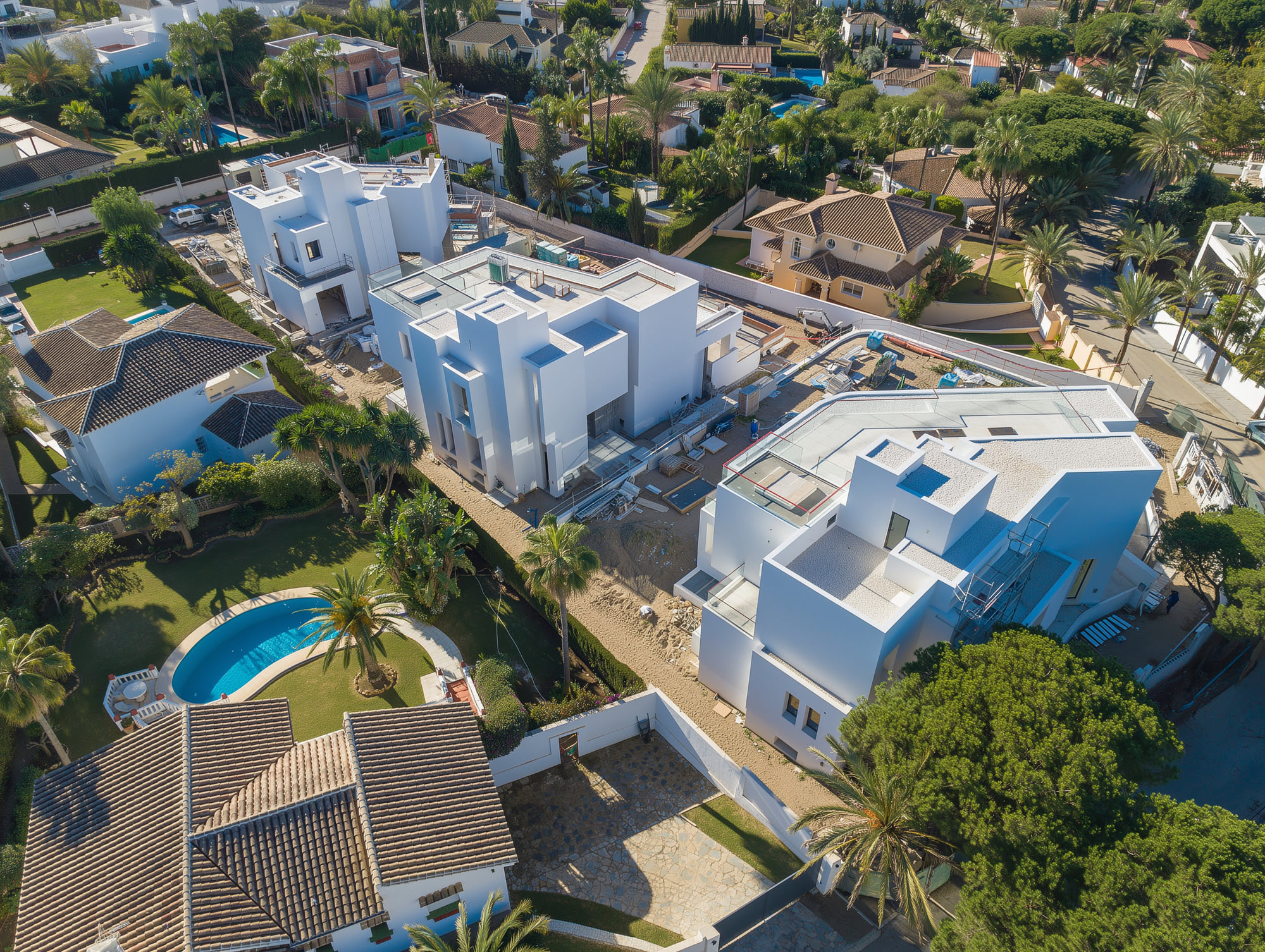 Drone view of the three M94 contemporary villas in Marbella East with pools, terraces and landscaped plots