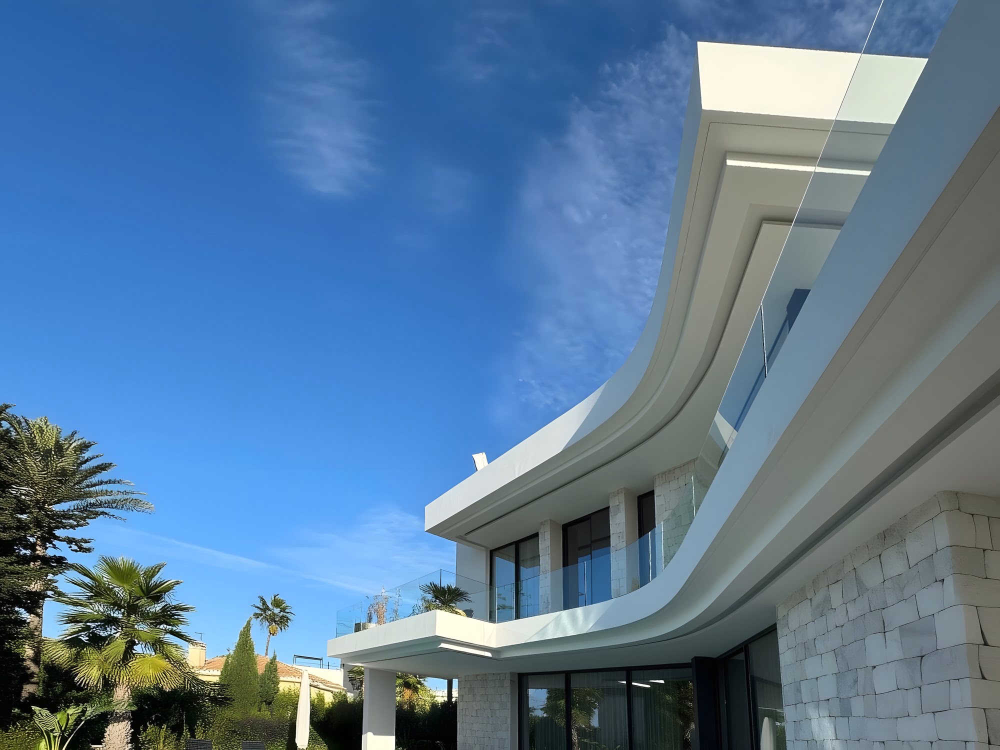 Low angle view of curved rooflines and natural stone cladding at M94 in Marbella East