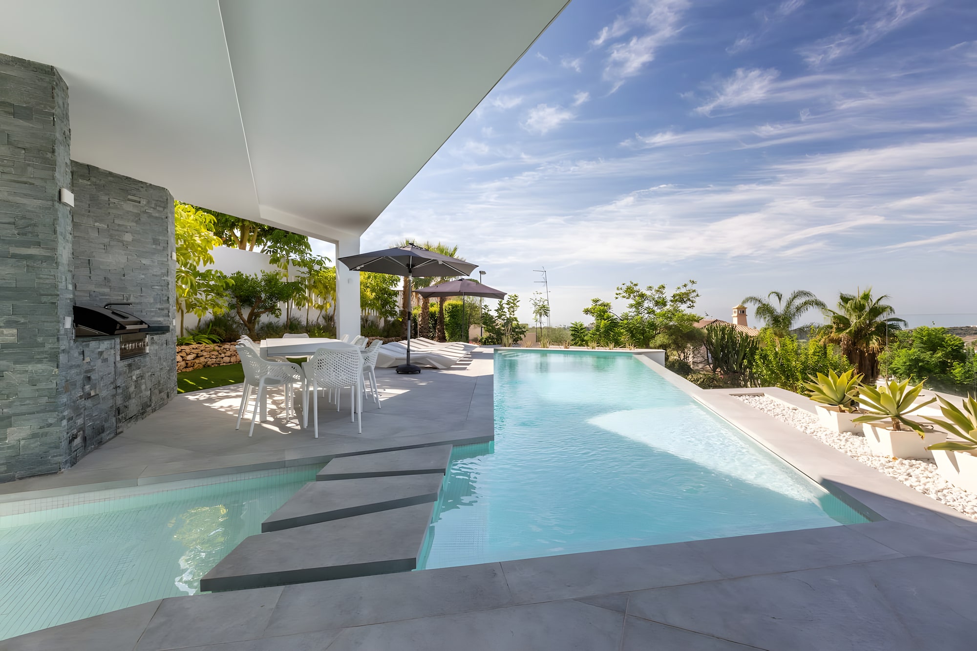 Covered terrace and long linear pool at Villa Origami with shaded lounge edge and open views