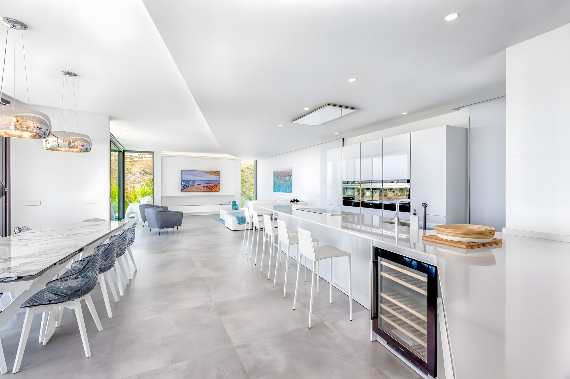 Open-plan kitchen and dining space at Villa Origami with large island, stone flooring and panoramic glazing