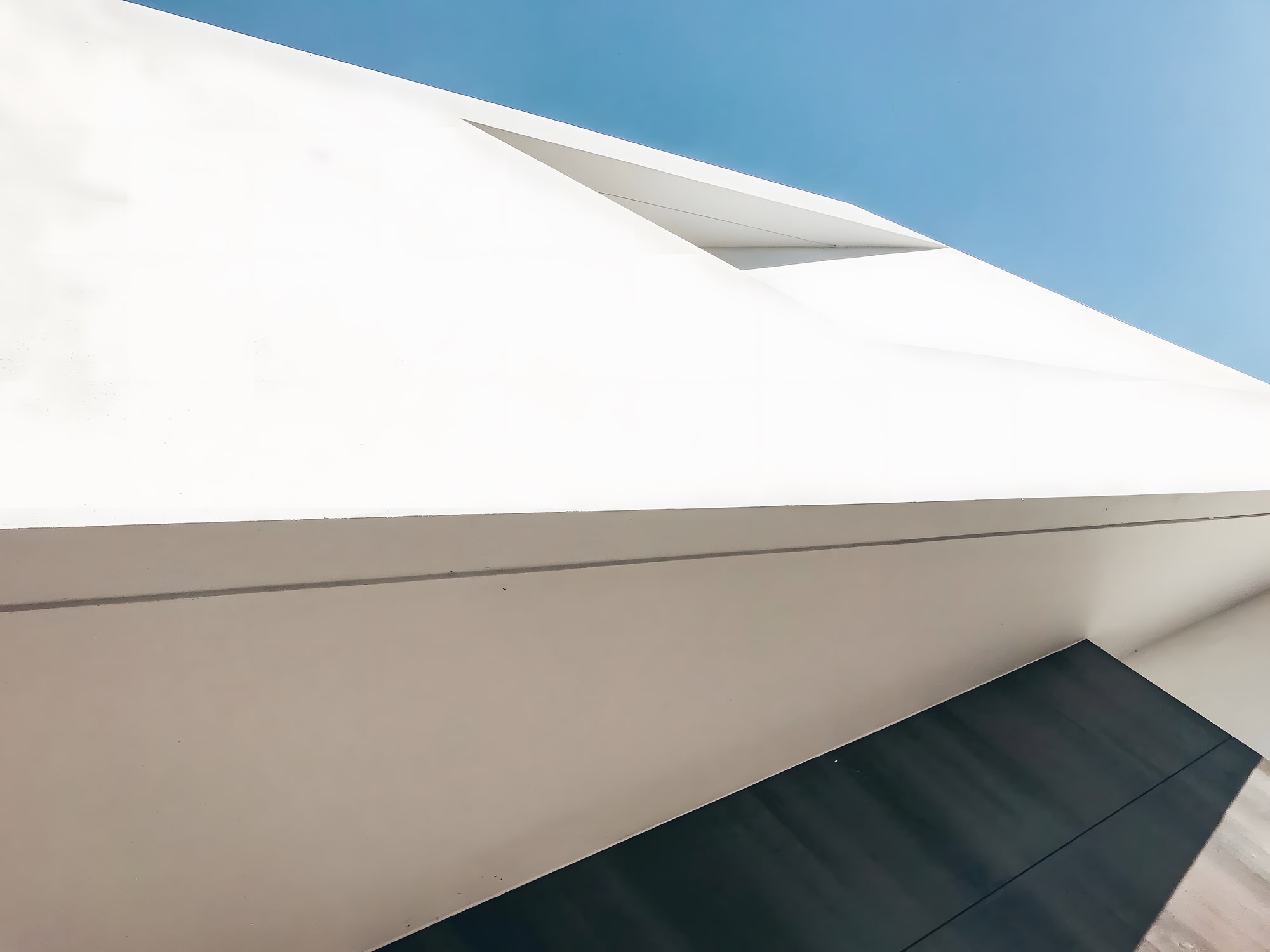 Close architectural detail of Villa Origami roofline with crisp folded soffit and white render finish