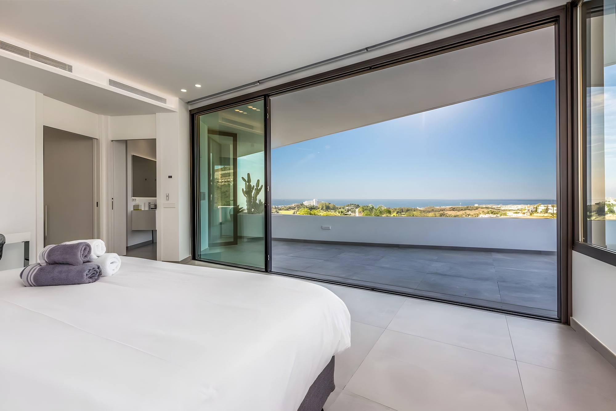 Bedroom suite at Villa Origami opening to a panoramic terrace with distant views over Benahavís