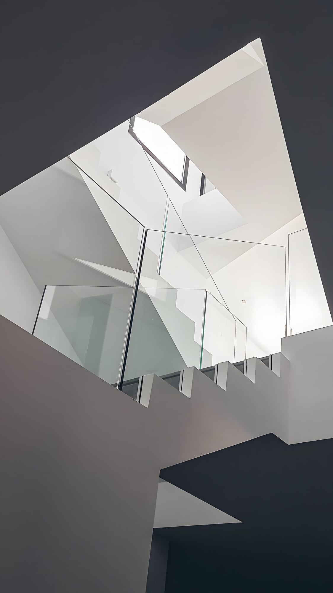 Interior stair void at Villa Origami with angular skylight geometry and monochrome architectural composition
