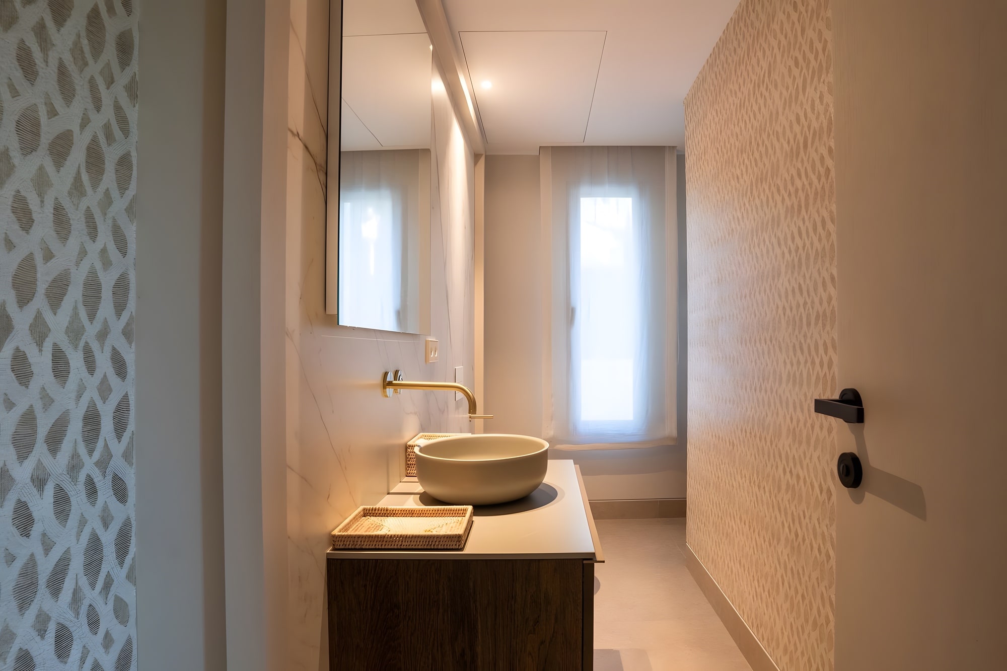 Guest bathroom with sculpted basin, textured wall finish and warm indirect lighting