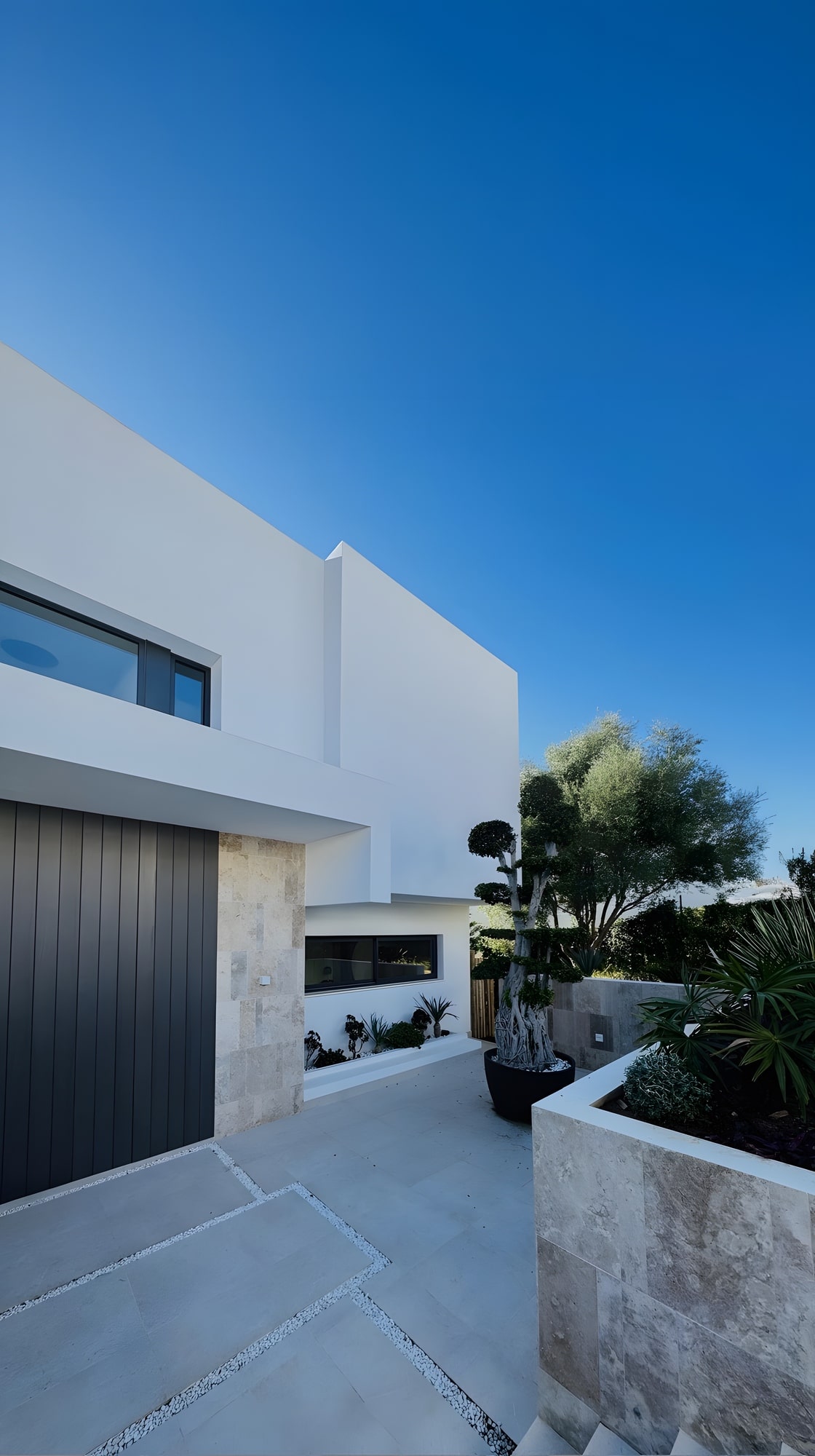 Side arrival perspective showing the garage volume, access court and crisp white architecture