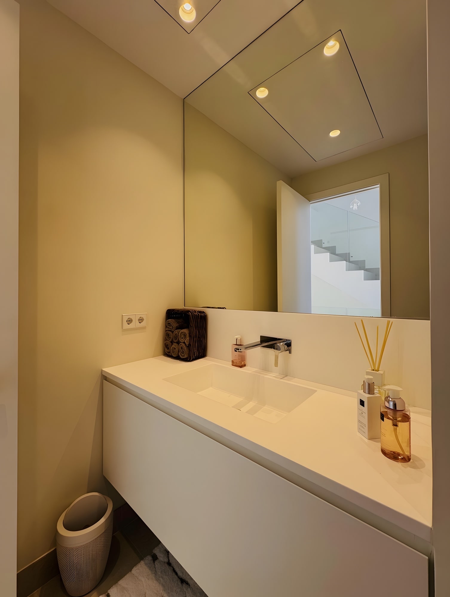 Minimal bathroom with bespoke vanity, warm lighting and sculpted white surfaces