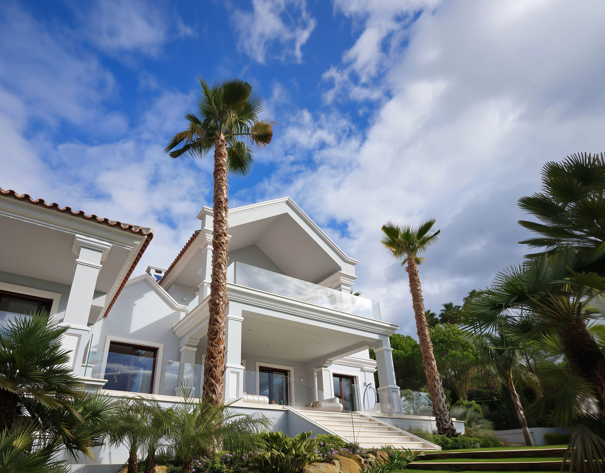 Angled exterior view of Villa Tanya showing classical Mediterranean volumes, palm trees and landscaped forecourt
