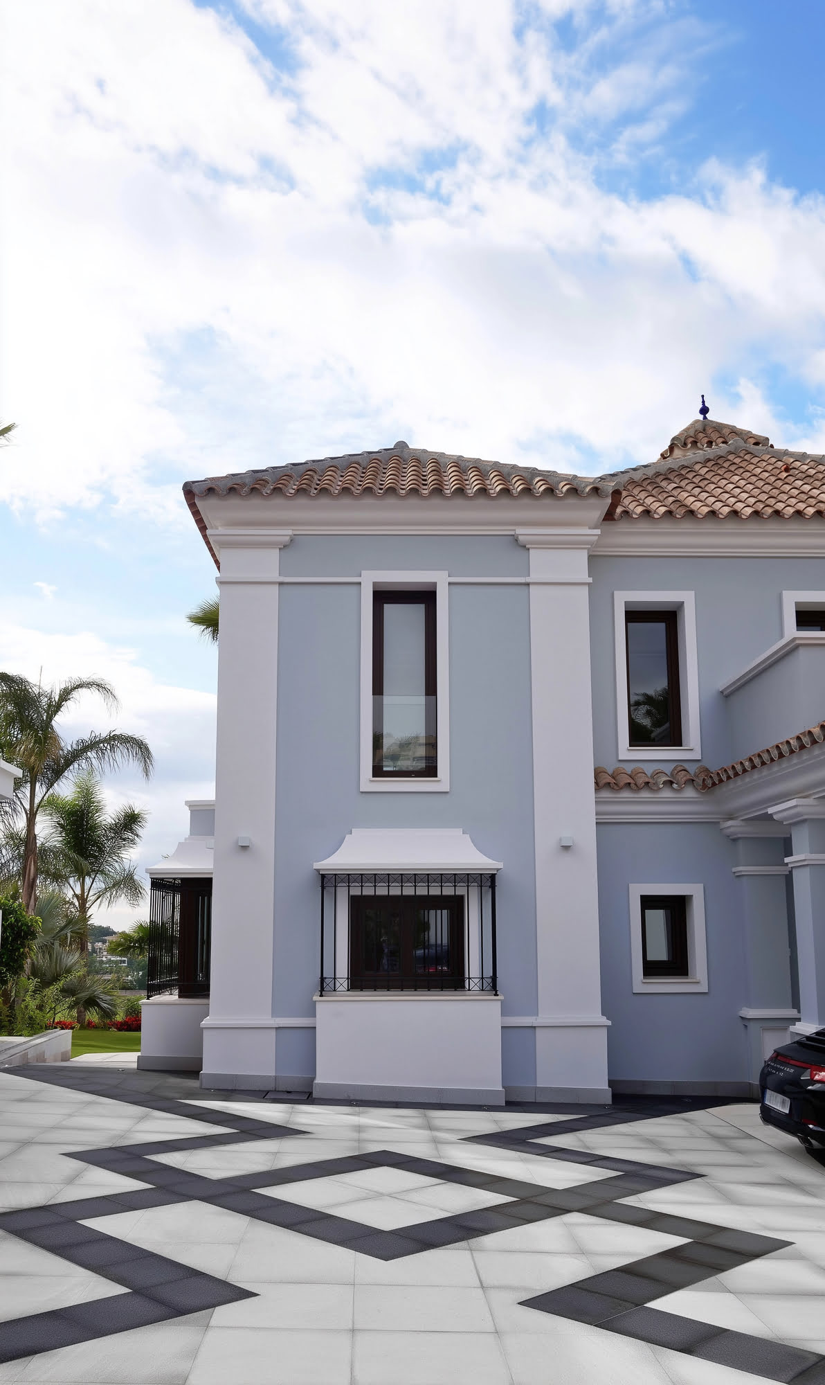 Side façade of Villa Tanya with classical windows, white rendered walls and patterned entrance court