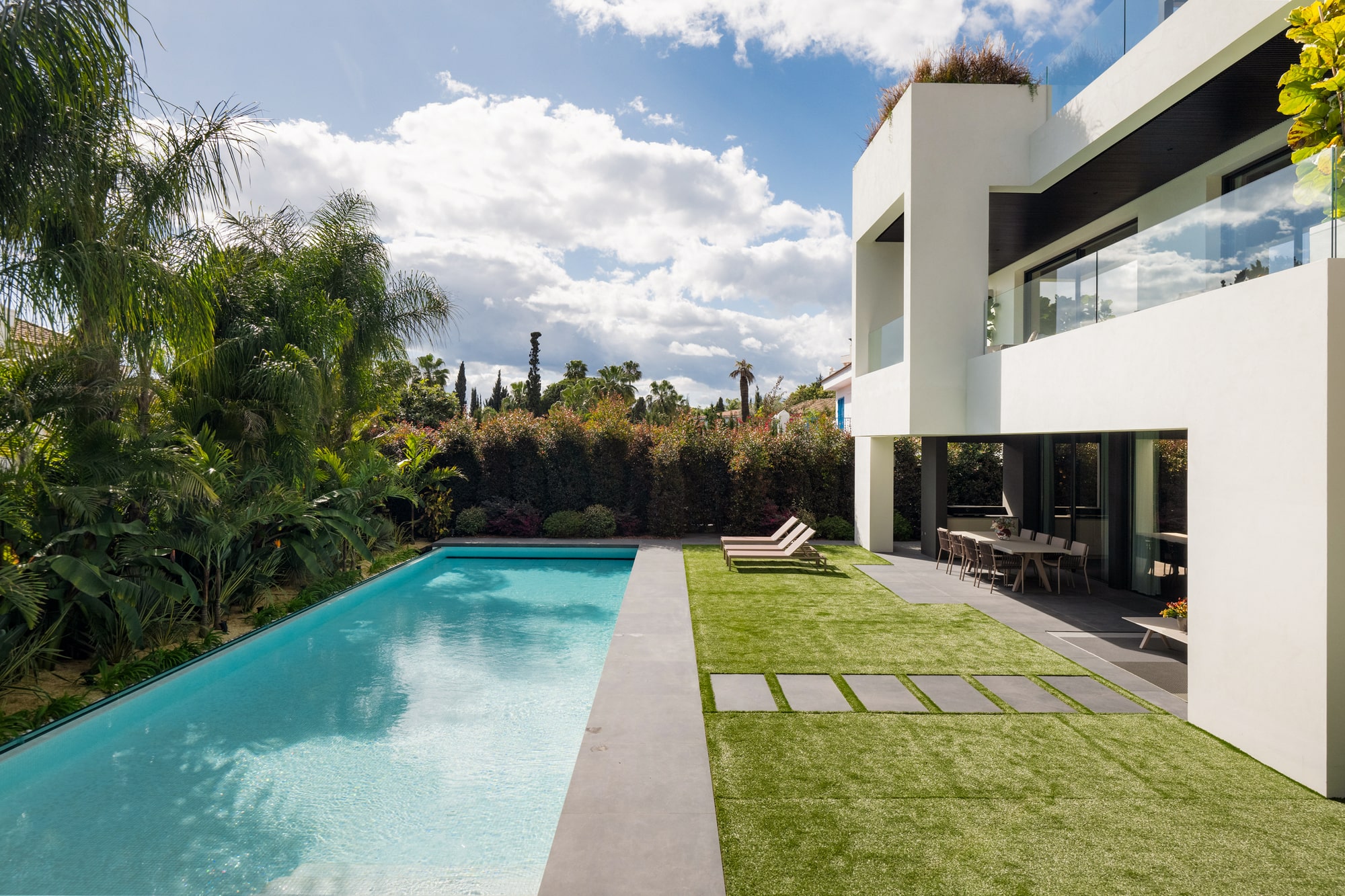 Linear poolside view at Casa Velázquez highlighting water, lawn and the calm horizontality of the villa