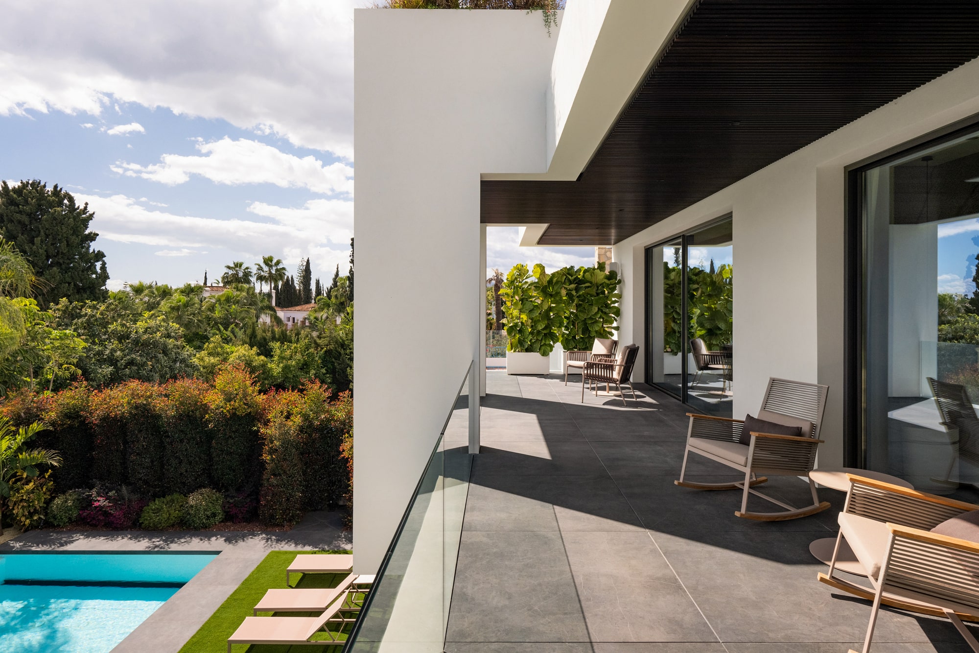 Covered outdoor terrace at Casa Velázquez with lounge seating, strong shadow lines and direct connection to the pool