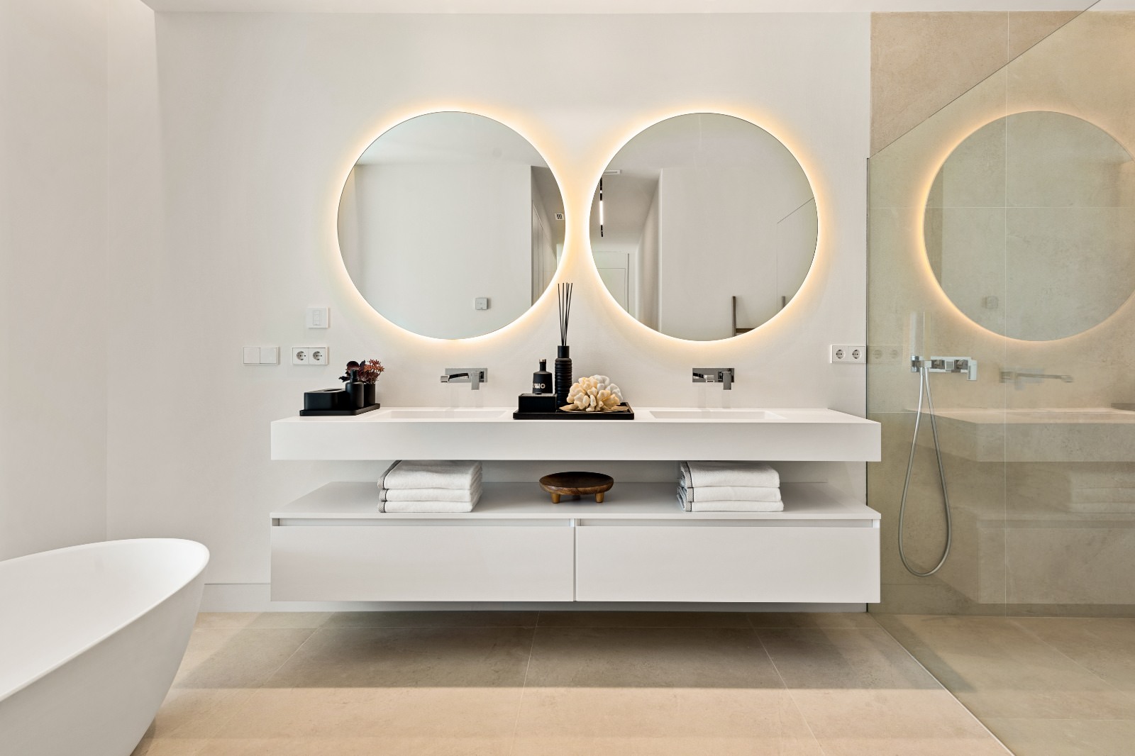 Bathroom at VIDA DEL MAR with floating vanity, circular mirrors and softly lit stone finishes