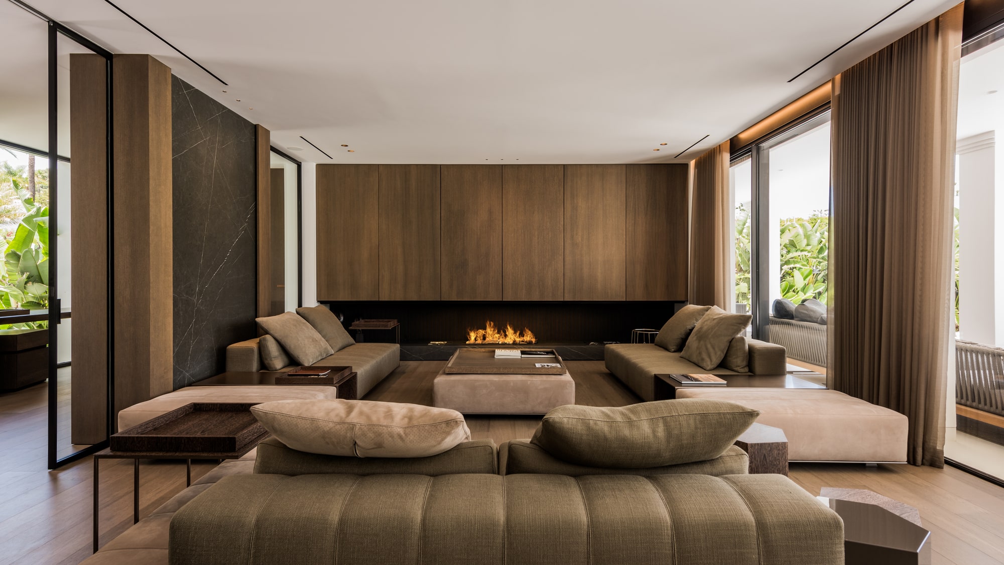 Secondary lounge space at Villa Zarina with fireplace wall, bespoke furniture and a calm palette of stone, timber and textiles