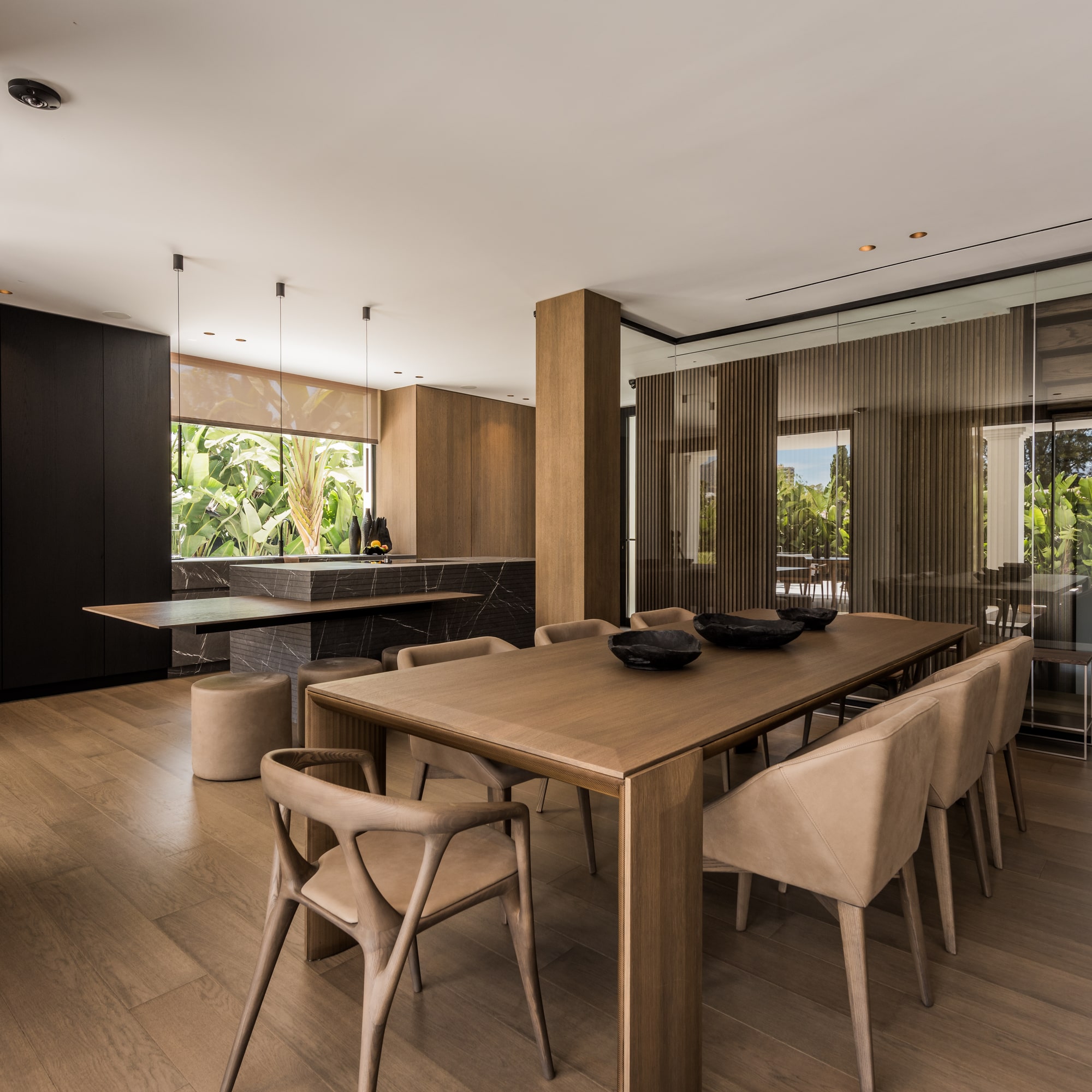 Open-plan dining and kitchen area at Villa Zarina with sculptural table, sliding glass openings and refined material continuity