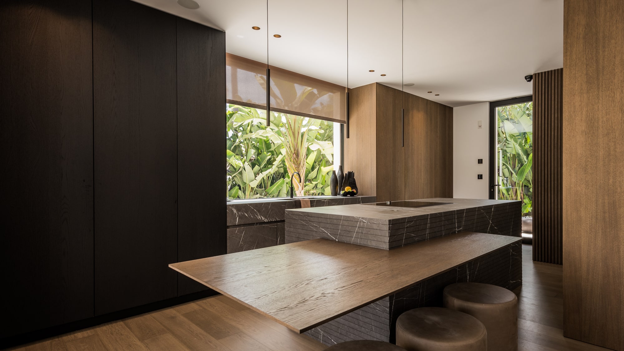 Kitchen island detail at Villa Zarina highlighting natural stone surfaces, dark joinery and precise contemporary craftsmanship