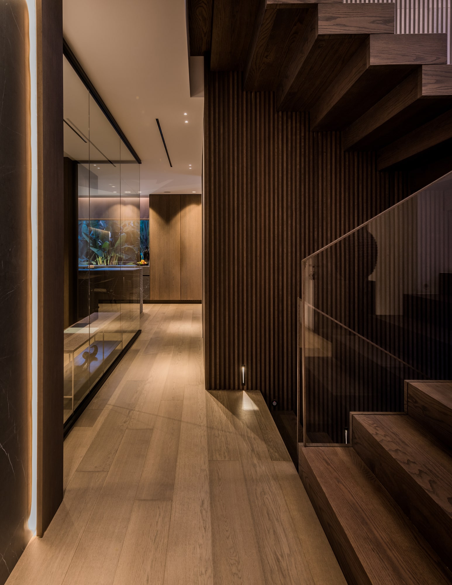 Interior corridor beside the staircase at Villa Zarina, defined by dark timber panelling, soft lighting and strong architectural rhythm