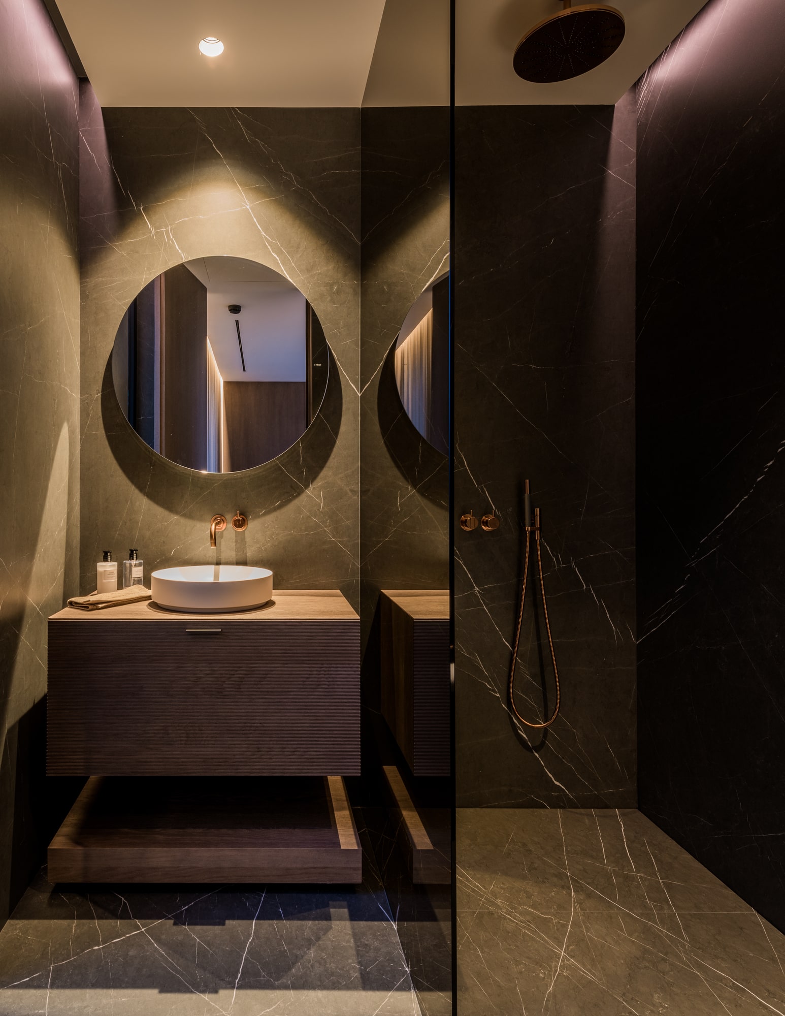 Atmospheric bathroom view at Villa Zarina with rounded mirror, dark-toned finishes and intimate lighting composition
